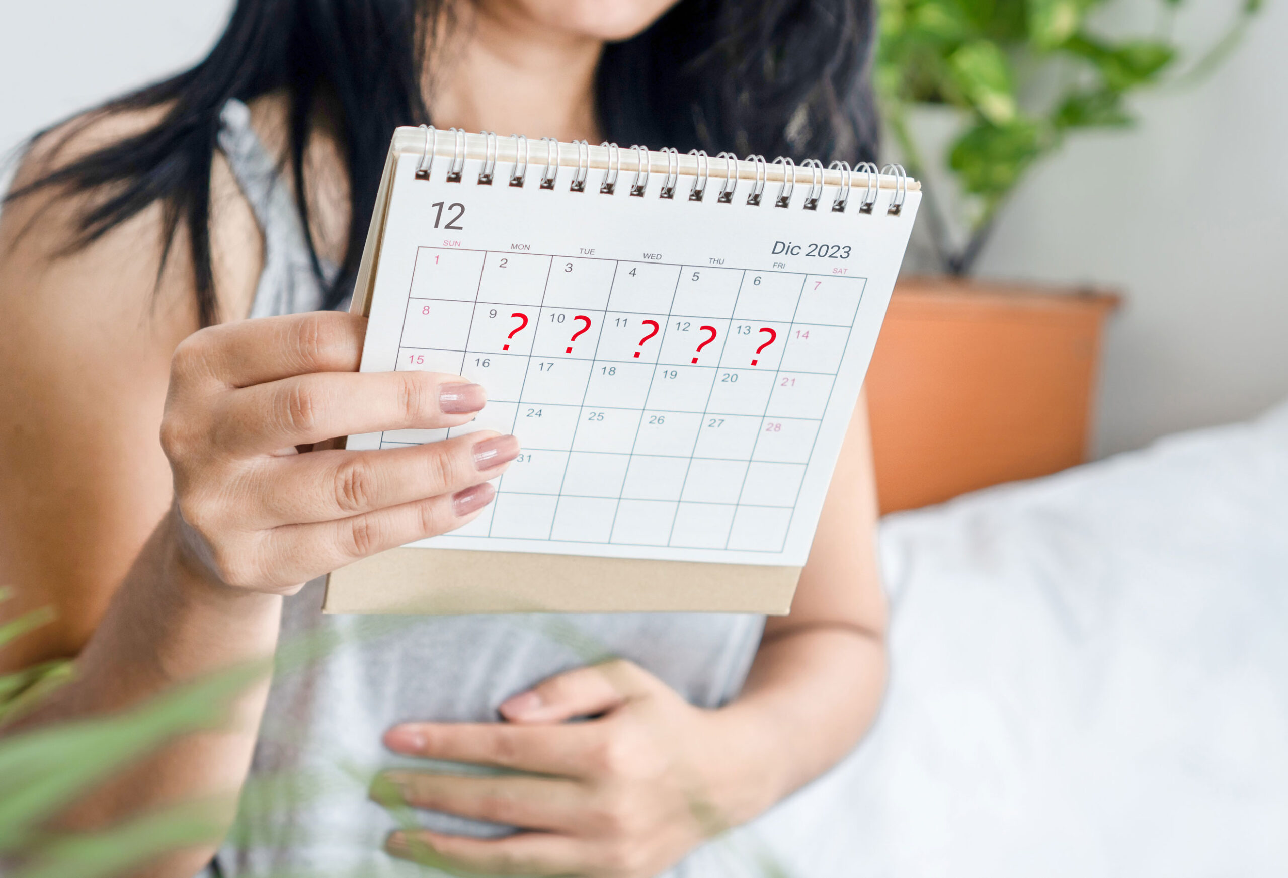 Donna con sintomi di gravidanza controlla i giorni di ritardo delle mestruazioni sul calendario
