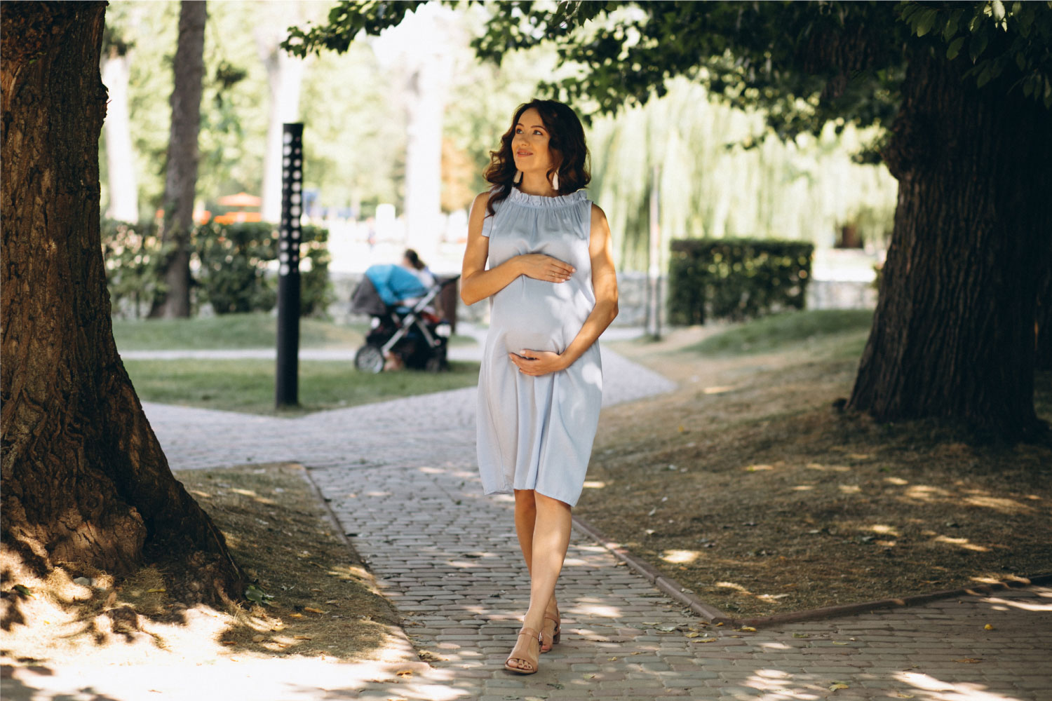 Donna incinta che sorride mentre cammina in un parco