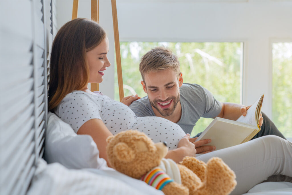 Mamma e papà che leggono libro ad alta voce al bimbo nel pancione