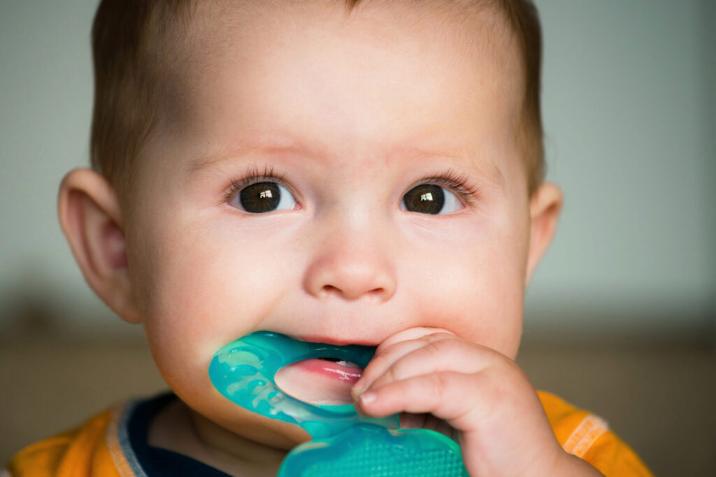 Bambino che si massaggia le gengive con un anello di gomma morbida in attesa che spuntino i primi dentini